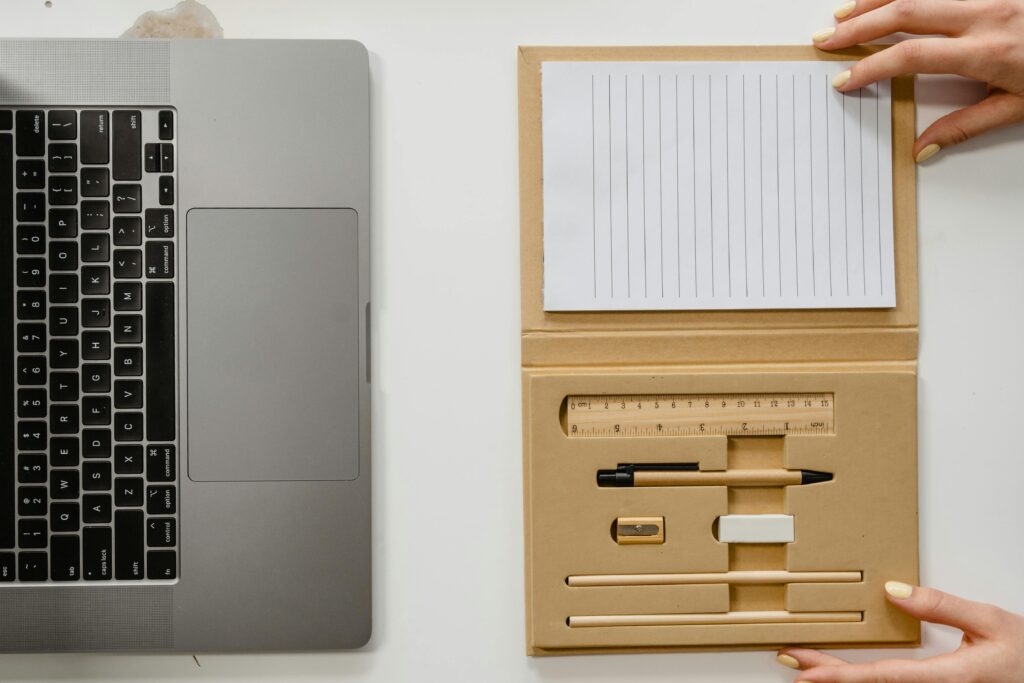 Top view of a neatly arranged laptop and stationery set on a white surface, ideal for productivity.