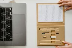 Top view of a neatly arranged laptop and stationery set on a white surface, ideal for productivity.