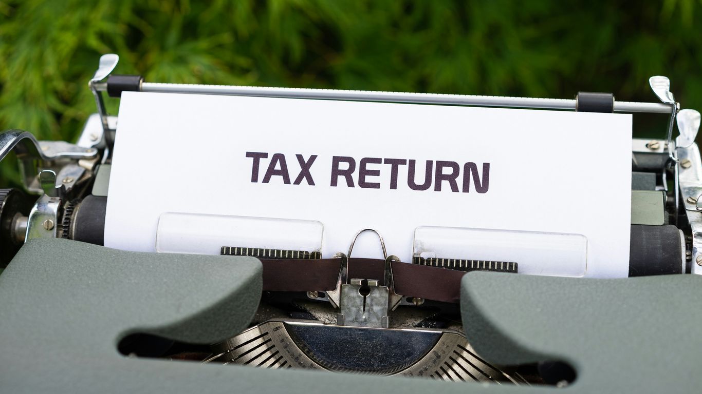 a close up of a typewriter with a tax return sign on it